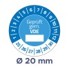 A képen egy kék kör alakú címke látható, amely tanúsítást jelöl a 'Geprüft gem. VDE' szöveggel és 20 mm átmérővel. A címke kerülete körül számozott jelölések találhatók, 1-től 30-ig terjedve.