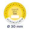 A képen egy kör alakú mérőműszer látható sárga háttérrel, amely méréseket jelez, középen a 'Geprüft gem. VDE' felirattal, valamint 1-től 30-ig terjedő számokkal a szélén. Az átmérője Ø 30 mm.