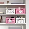 A kép egy szépen rendezett polcot mutat színes tárolókosarakkal. A kosarak németül vannak felcímkézve, és különböző irodaszereket tartalmaznak, mint például ollók, jegyzetek és színek.