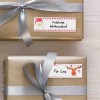 A képen két gyönyörűen becsomagolt ajándék látható arany papírban, mindegyik ezüst szalaggal díszítve. Az egyik ajándékhoz egy 'Fröhliche Weihnachten!' feliratú címke tartozik, amelyen egy Mikulás ábra is szerepel, míg a másik 'Für Lina' felirattal van ellátva, és egy rénszarvas ábrázolás található rajta.
